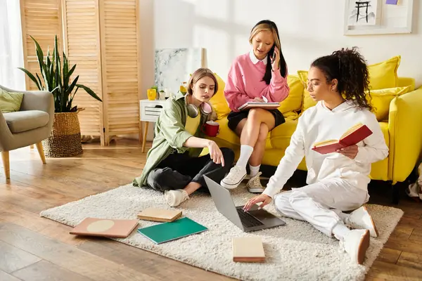 A diverse group of teenage girls gather on a vibrant yellow couch, chatting and studying together in their cozy home. — Stock Photo