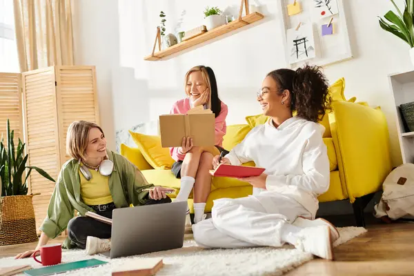 Meninas adolescentes multiculturais se sentam juntas em um sofá amarelo, estudando e compartilhando conhecimento em um ambiente acolhedor em casa. — Fotografia de Stock