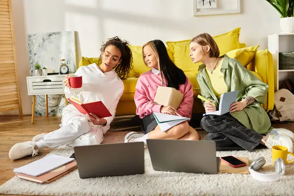 Um trio diversificado de adolescentes envolvidos em sessão de estudo virtual, sentados com laptops no chão. — Fotografia de Stock