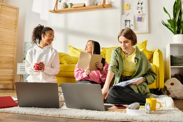 Young women of different ethnicities sit on the floor with laptops, engrossed in studying together from home. — Stock Photo