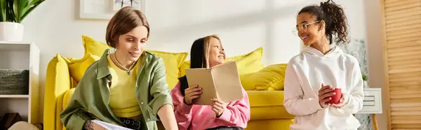A diverse group of young women sit and study on a vibrant yellow couch, sharing laughter and knowledge. — Stock Photo