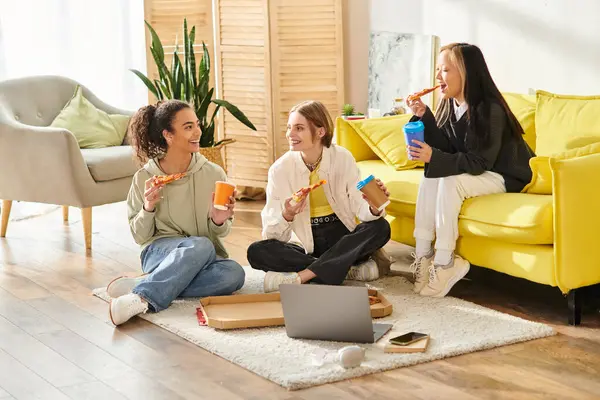 A diverse group of teenage girls enjoy each others company while sitting and chatting on a wooden floor. — Stock Photo