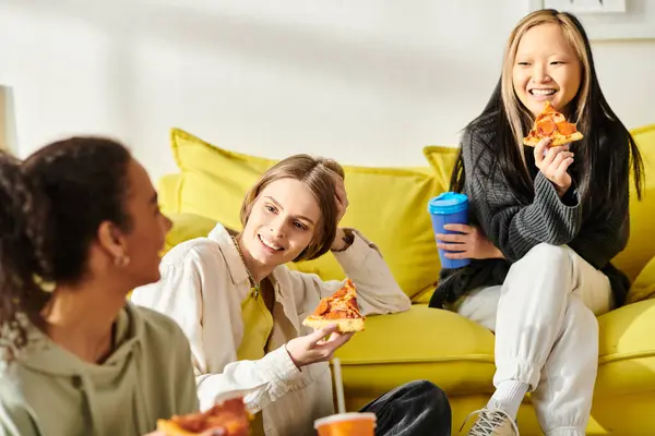 Un grupo diverso de adolescentes se sientan juntas en un vibrante sofá amarillo, simbolizando amistad y unión. - foto de stock