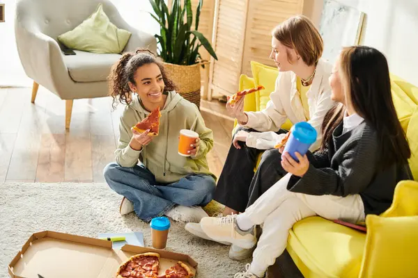 Un groupe diversifié d'adolescentes s'assoient sur un canapé jaune, bavardant et riant, incarnant la beauté de l'amitié et de la convivialité. — Photo de stock