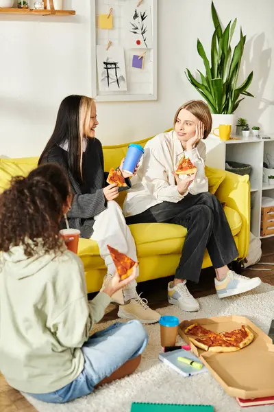 A diverse group of teenage girls relaxing and chatting on a bright yellow couch, embodying friendship and togetherness. — Stock Photo