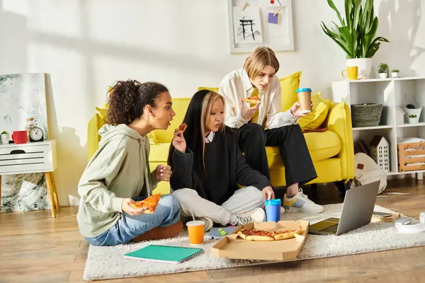Multicultural teenage girls lounging happily on a vibrant yellow couch in a cozy indoor setting. — Stock Photo