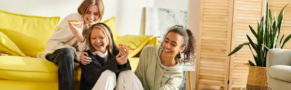 A woman and two interracial teenage girls sitting together on a vibrant yellow couch, enjoying each others company. — Stock Photo