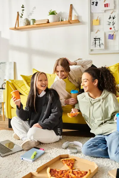 Diverse young women enjoy each others company on a bright yellow couch in a cozy living room setting. — Stock Photo