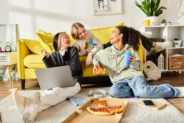 A diverse group of teenage girls laugh and chat on a couch, enjoying pizza and drinks in a cozy home setting. — Stock Photo