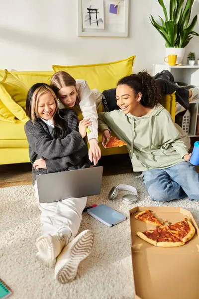 Un grupo diverso de adolescentes interracial se reunieron en el piso compartiendo pizza y disfrutando de la compañía de los demás. - foto de stock