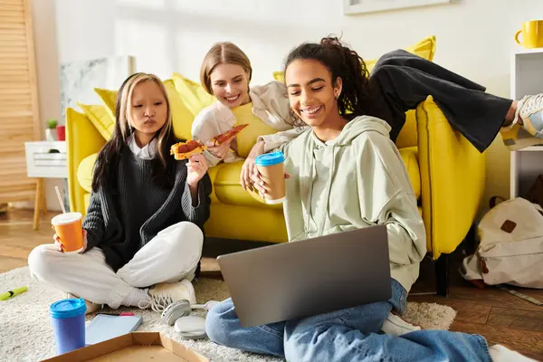 A diverse group of teenage girls seated on the floor, engrossed with a laptop while fostering friendship and connection. — Stock Photo