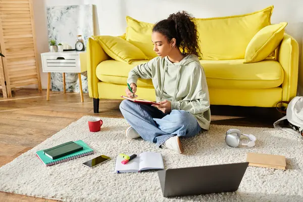 Uma adolescente envolvida em e-learning, senta-se no chão com um laptop. — Fotografia de Stock