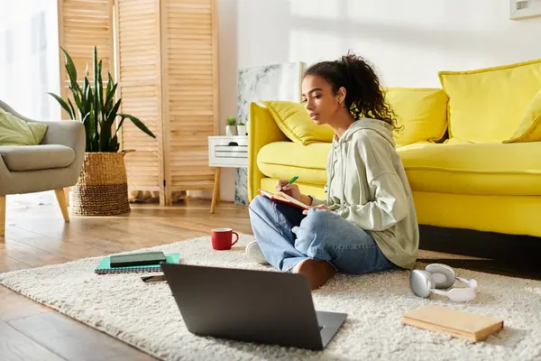 Une adolescente engagée dans l'apprentissage en ligne, assise sur le sol avec un ordinateur portable. — Photo de stock