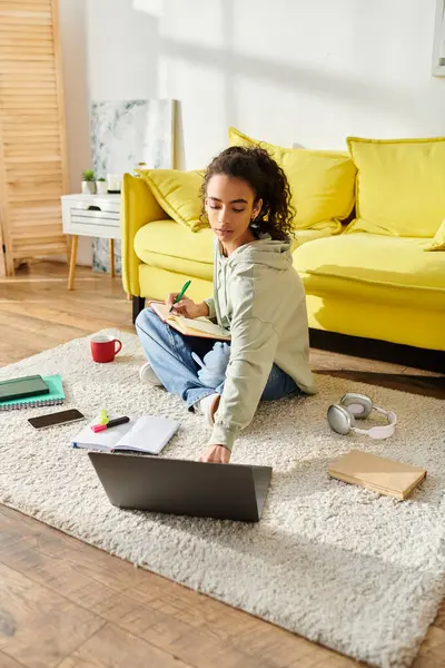 Ein Mädchen im Teenageralter sitzt auf dem Boden, versunken in E-Learning auf ihrem Laptop. — Stockfoto