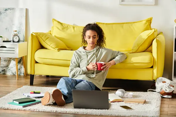 Uma adolescente envolvida em e-learning em casa, sentada no chão trabalhando em seu laptop. — Fotografia de Stock