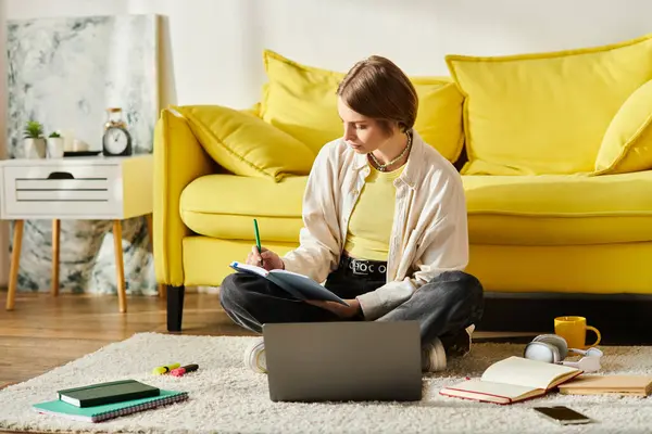 Девочка-подросток сидит на полу перед ноутбуком и увлекается электронным обучением дома.. — стоковое фото