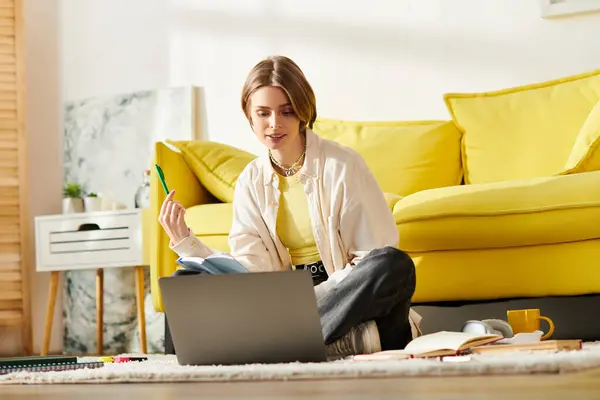 Una adolescente absorta en el e-learning, sentada en el suelo con un portátil. - foto de stock