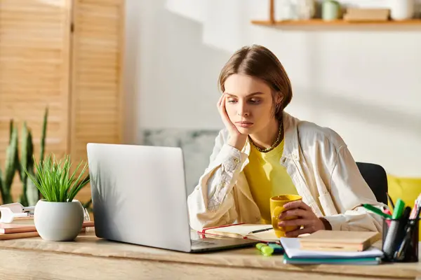 Ein konzentriertes Teenager-Mädchen, das an einem Holztisch mit offenem Laptop vor sich zum E-Learning lernt. — Stockfoto
