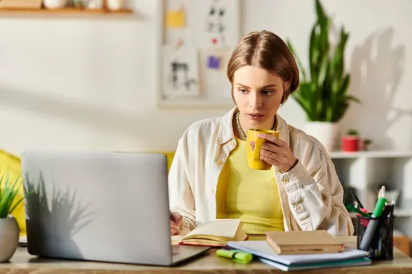 A teenage girl sits at a desk with a laptop and a cup of coffee, focused on her e-learning session. — Stock Photo