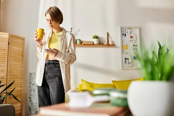 A serene moment as a teenage girl stands in her cozy living room, enjoying a cup of coffee during her e-learning session. — Stock Photo