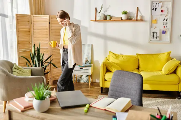 Девочка-подросток стоит в гостиной рядом с жёлтым диваном и занимается электронным обучением со своим ноутбуком.. — стоковое фото