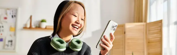 Eine junge asiatische Studentin jongliert mühelos mit E-Learning, während sie ein Smartphone in der Hand hält. — Stockfoto