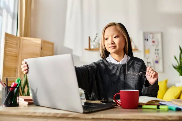 A young Asian woman deeply engrossed in e-learning, sitting in front of her laptop at home. — Stock Photo