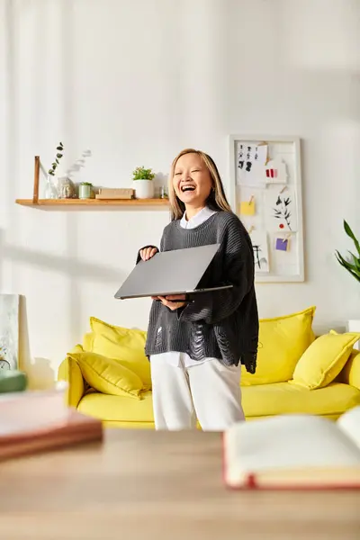 Uma jovem asiática está em uma sala de estar, profundamente envolvida em e-learning, segurando um laptop. — Fotografia de Stock