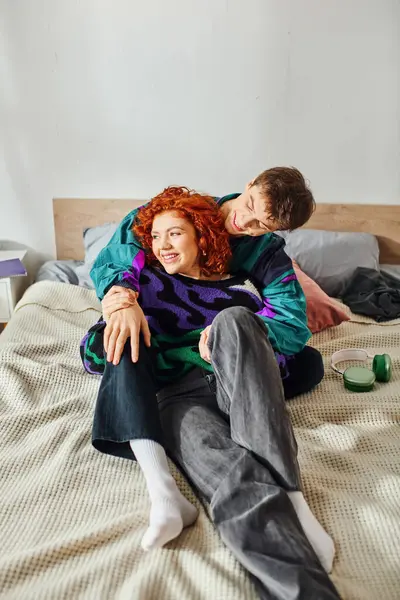 Alegre bien parecido pareja en casual atuendos pasando gran tiempo juntos y abrazando mientras en la cama - foto de stock