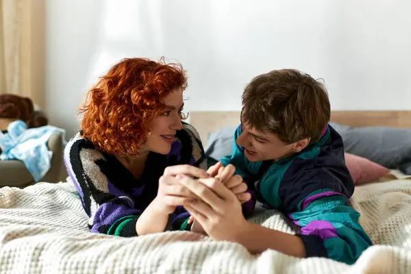 Cheerful trendy couple in casual vivid outfits lying in bed together while spending time at home — Stock Photo