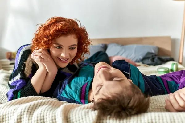Rousse séduisante femme regardant avec amour son beau petit ami tout couché sur le lit ensemble — Photo de stock