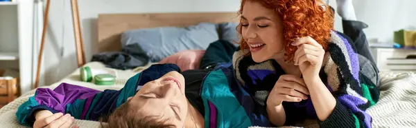Séduisant couple joyeux dans des vêtements confortables à la mode couché dans le lit ensemble relaxant à la maison, bannière — Photo de stock