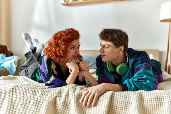 Séduisant couple joyeux dans des tenues décontractées vives passer du temps ensemble tout en étant couché dans le lit à la maison — Photo de stock