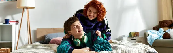 Seductora mujer pelirroja tumbada en la cama junto a su amante novio con auriculares en casa, pancarta - foto de stock