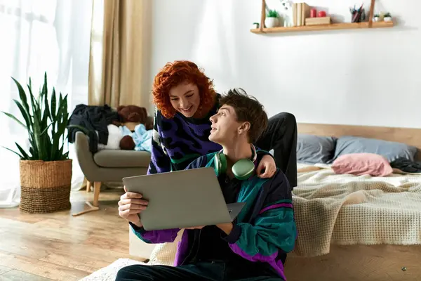 Sedutor mulher de cabelos vermelhos sentado na cama e passar o tempo no laptop com seu namorado bonito — Fotografia de Stock