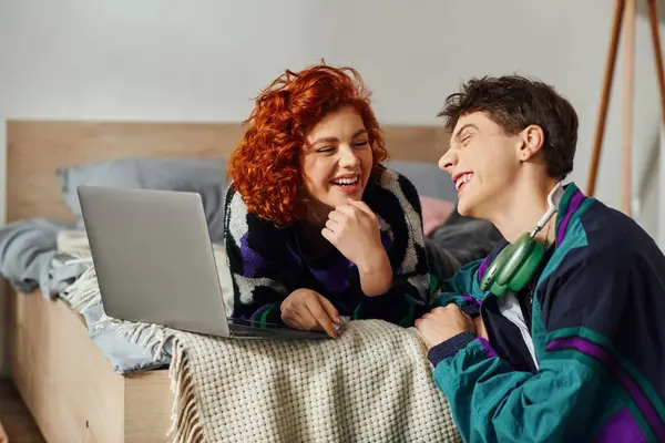 Beautiful jolly girlfriend in vibrant attire spending time at laptop with her loving boyfriend — Stock Photo
