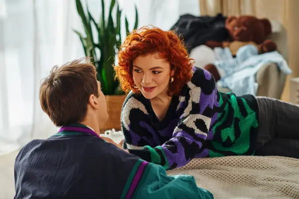 Joyous alluring trendy couple in cozy vivid attires looking lovingly at each other while at home — Stock Photo