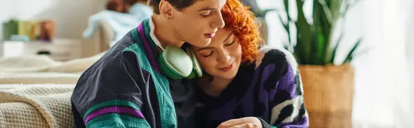 Liebender Mann mit Kopfhörern, der seine fröhliche rothaarige Freundin zu Hause umarmt, Banner — Stockfoto