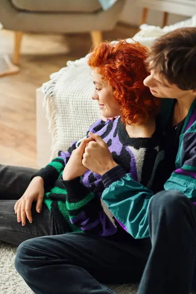 Good looking jolly man in casual attire hugging his beautiful merry girlfriend while at home — Stock Photo