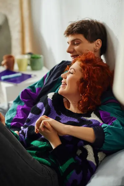Cheerful young man in cozy attire hugging lovingly his jolly beautiful girlfriend while in bed — Stock Photo