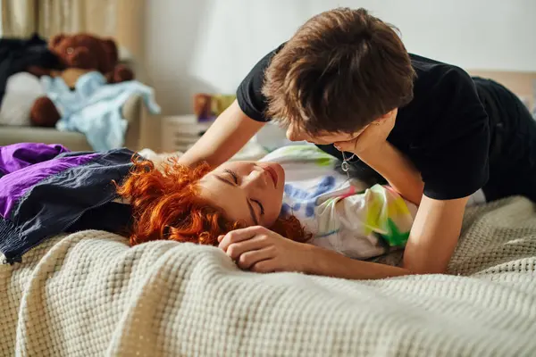 Loving appealing girlfriend and boyfriend preparing to kiss alluringly while lying on their bed — Stock Photo