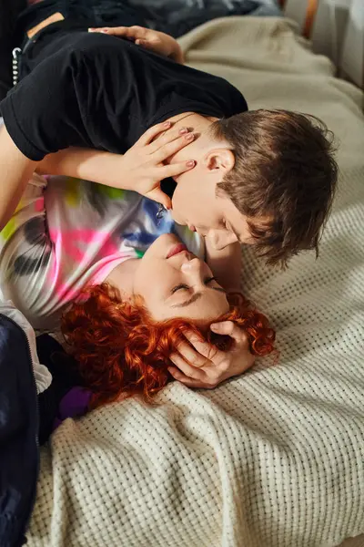 Beau couple de fantaisie en vêtements de maison se préparant à embrasser avec amour tout en étant couché sur le lit ensemble — Photo de stock