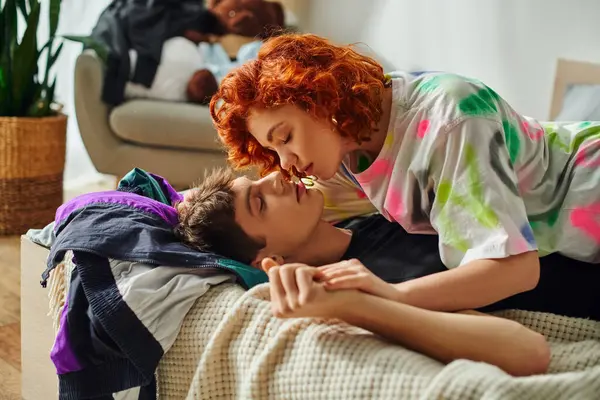 Красивая заботливая пара в яркой домашней одежде готовится поцеловаться соблазнительно, лежа на кровати вместе — стоковое фото