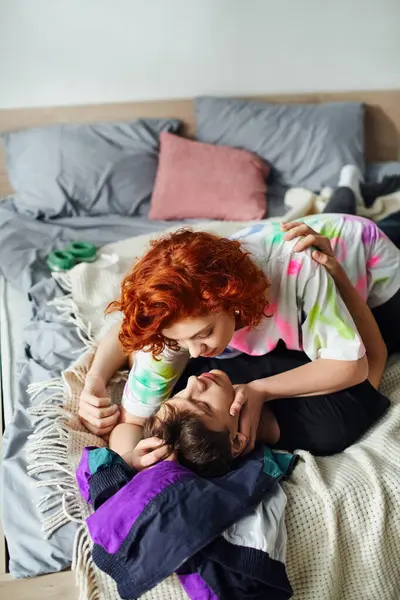 Appealing young couple in cozy homewear preparing to kiss lovingly while lying on bed together — Stock Photo