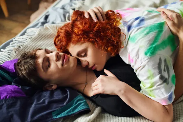 Good looking jolly young couple in casual attire hugging seductively while lying on bed at home — Stock Photo