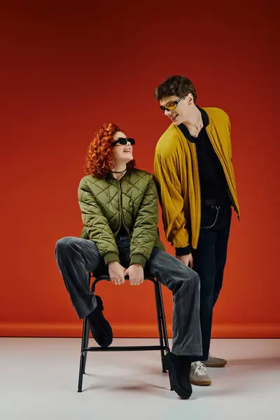 Alluring red haired woman in fashionable attire sitting on chair next to her handsome boyfriend — Stock Photo