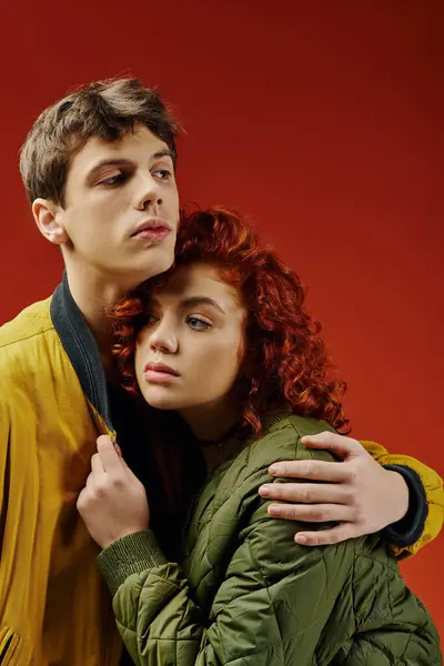 Good looking couple in casual vibrant clothing posing together on red backdrop and looking away — Stock Photo