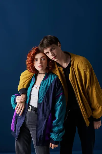 Appealing couple in vibrant casual outfits posing together and looking at camera on blue backdrop — Stock Photo