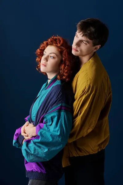 Appealing loving couple in casual fashionable attire hugging alluringly on dark blue backdrop — Stock Photo