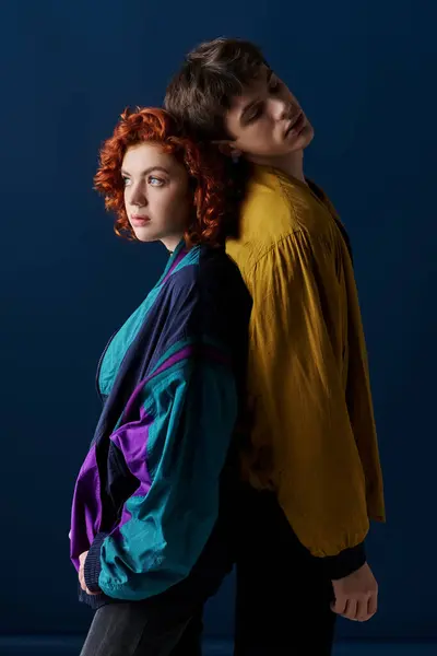 Appealing boyfriend and girlfriend posing back to back and looking away on dark blue background — Stock Photo